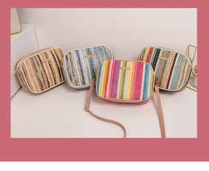 Close-up of four colorful striped straw woven crossbody bags with metal zipper closure