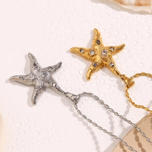 Detail of 18K gold and silver starfish pendants with zircon stones on ball chains