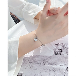 Detail of silver steel bracelet with shell-inlaid heart and engraved Love pendant