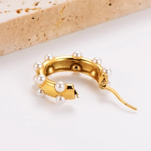 Vintage 18k gold U-shaped hollow earrings with white pearls on a minimalist stone base