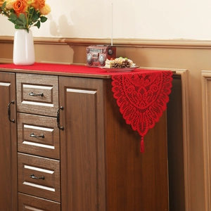 Red Christmas lace table runner with intricate hollow patterns and elegant tassels