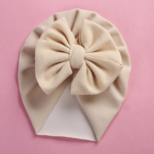 Close-up of cream white cashmere-like baby beanie featuring a large fabric bow
