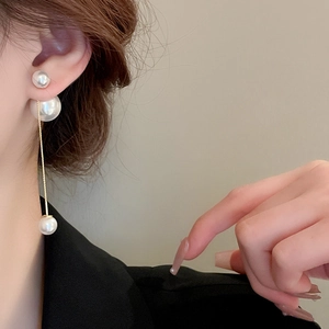 Close-up of gold-plated long pearl tassel earrings with fine metal chain on a model