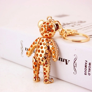 Golden hollow bear keychain with crystal rhinestones on a vintage book background