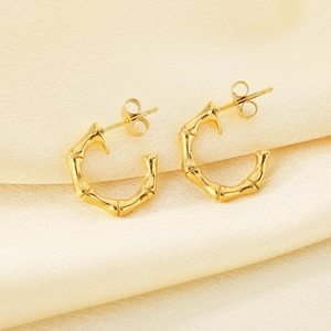 Elegant gold bamboo joint C-shape hoop earrings on a yellow silk fabric background