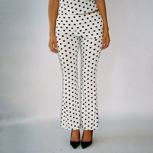 Détail du pantalon évasé blanc à pois noirs avec taille haute et talons élégants