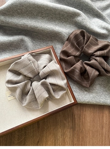 Detail of striped fabric scrunchies in gray and brown on a rustic wooden tray
