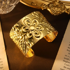 Goldenes böhmisches Armband mit floralem Reliefmuster in einem Vintage-Stillleben-Setup