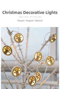 Detail of wooden reindeer LED string lights hanging on a snowy branch with warm glow