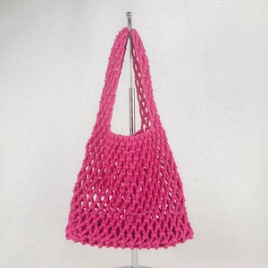 Detailed close-up of rose pink crochet net beach bag featuring a large mesh diamond pattern
