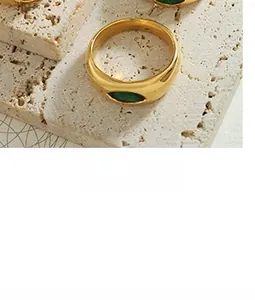 Detailed close-up of a chunky gold-plated ring featuring an oval green stone inlay