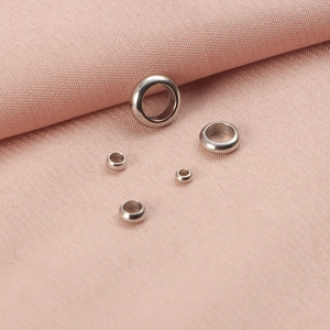 Polished stainless steel round spacer beads for DIY jewelry making on pink fabric