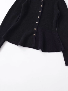 Detail of rib-knit cardigan featuring amber texture buttons and elegant peplum hem detail