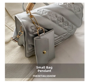 Detailed view of silver quilted shoulder bag with floral pattern and gold hardware accents