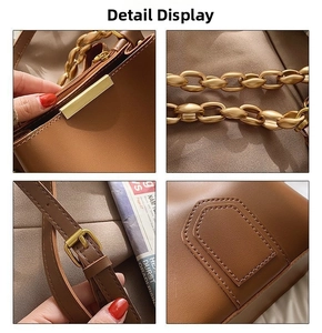 Detail view of brown leather bucket bag with gold chain and refined stitching details