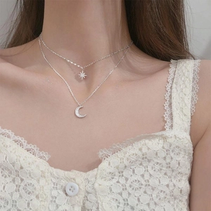 Close-up of double-layer silver necklace featuring sparkling star and crescent moon pendants