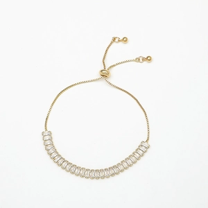 Detail of adjustable gold slider bracelet featuring rectangular cut clear zircon stones