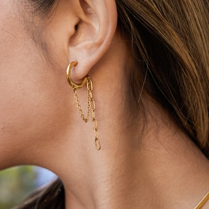 Minimalist gold stainless steel C-hoop chain drop earrings worn by a model in outdoor light