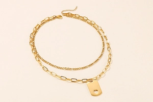 Detail of gold double-layer necklace with rectangular pendant and hollow heart charm