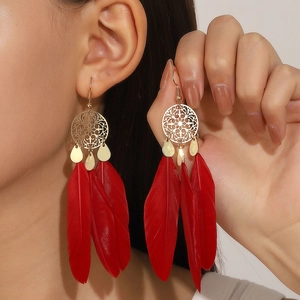Detail of bohemian long feather earrings in red and gold on a fashion model