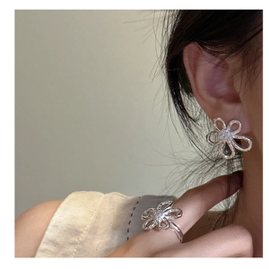 Close-up of S925 silver flower stud earrings and matching ring with zircon inlay