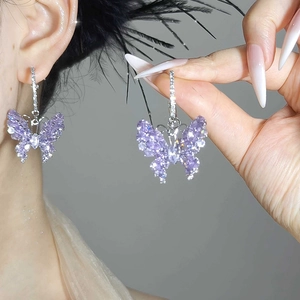 Detail of purple butterfly earrings with cubic zirconia inlay worn by a model