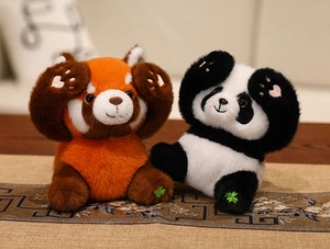 Macro shot of plush red panda and giant panda toys with green clover embroidery detail
