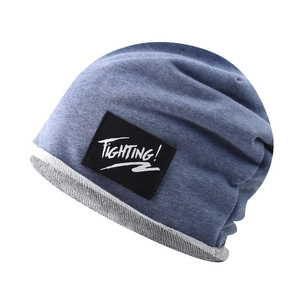 Detail of blue cotton knit beanie featuring a black 'FIGHTING!' woven label and cuff