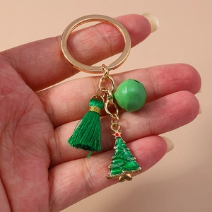 Detail of Christmas keychain with green tassel, bell, and tree pendant on gold ring