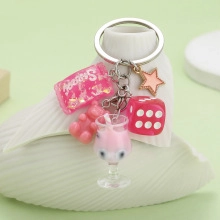 Detailed close-up of a pink resin keychain with sweet candy, gummy bear and dice charms