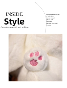 Close-up of white plush bunny doll showing detailed pink embroidered paw print patterns