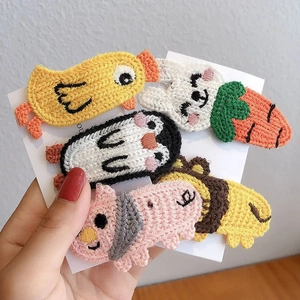 Dettaglio di un set di 5 fermagli per capelli lavorati a maglia con leone, maiale e papera