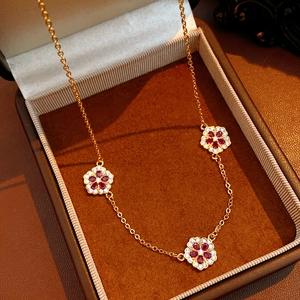 Dettaglio della collana floreale placcata oro 18K con pietre rosse e accenti di zirconi