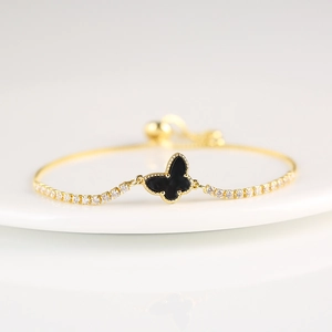 Detail of butterfly bracelet with gold frame, black center and white zircon inlay