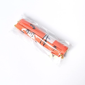 Detail of a rolled orange fabric banner with gold ends in transparent packaging
