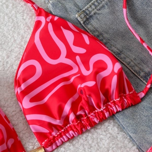 Close-up of red and pink printed bikini top with gold hardware and detailed stitching
