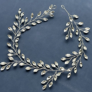 Macro detail of silver bridal hair vine with marquise crystals on dark leather background