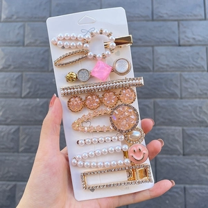 Close-up of hair clip set with pearls, pink rhinestones, and smile face charms