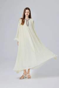 Détails de perlage et bordure en plumes blanches sur une robe maxi plissée ivoire