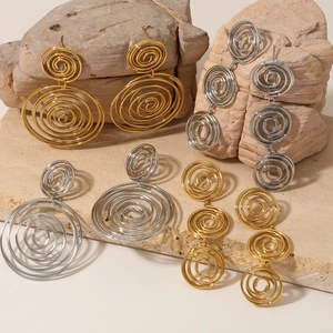 Exaggerated geometric gold and silver hoop earrings set displayed on natural stone