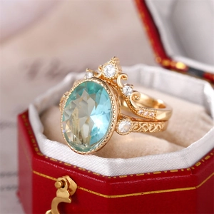 Gros plan détaillé d'un ensemble de bagues couronne dorées avec zircon bleu sur boîte