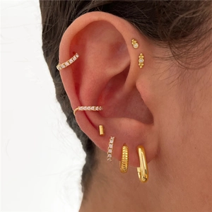 Close-up of gold S925 sterling silver ear studs and cuffs set with sparkling crystals
