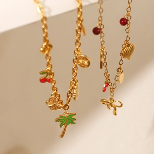 Close-up of gold stainless steel necklace featuring colorful palm tree and fruit charms
