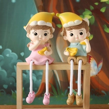 Close-up of cute resin couple ornaments wearing banana hats and sitting on wood