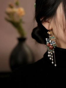 Gros plan de boucles d'oreilles papillon vintage avec grenade et pompons perles sur modèle