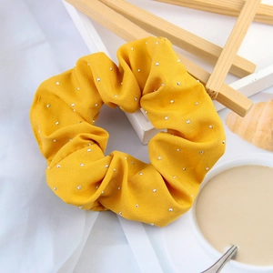 Detail of yellow fabric scrunchie with silver rhinestones on an aesthetic desktop