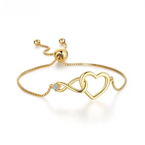 Detail of adjustable golden infinity heart bracelet with cubic zirconia on a white background