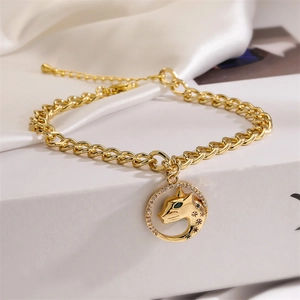 Close-up of golden Cuban link bracelet with sparkling leopard head pendant on silk