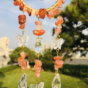Close-up of suncatcher with orange agate stones and butterfly crystals on gold metal ring