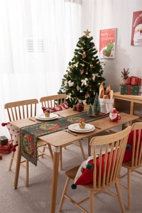 Detailed Christmas table runner with red plaid patterns and festive cushions in a cozy dining room